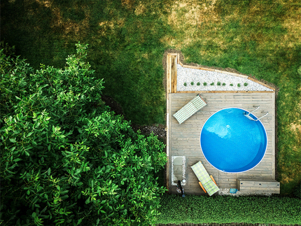 Letecký snímek s pohledem na bazén obložený terasovými prkny KI Duo v hnědé barvě, zakázková výroba Impregnace Soběslav. Letecký snímek s pohledem na bazén obložený terasovými prkny KI Duo v hnědé barvě, zakázková výroba Impregnace Soběslav.