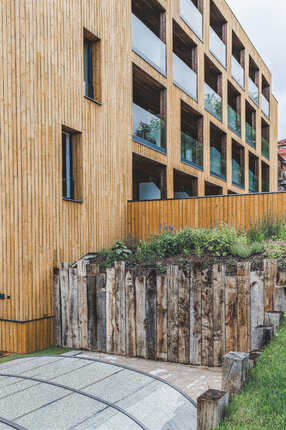 Fasádní obklad KI Trend v okrovém odstínu na budově luxusního hotelového komplexu, v popředí ohraničení terénu ze zahradních pražců. Realizace na zakázku Impregnace Soběslav. Fasádní obklad KI Trend v okrovém odstínu na budově luxusního hotelového komplexu, v popředí ohraničení terénu ze zahradních pražců. Realizace na zakázku Impregnace Soběslav.