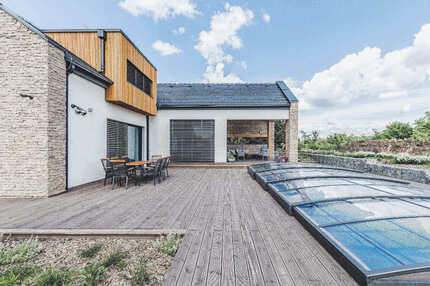 Terasová prkna KI Duo v šedé barvě na terase rodinného domu, v pozadí je vidět obložení budovu fasádním obkladem KI Trend v okrové barvě. Zakázková výroba Impregnace Soběslav. Terasová prkna KI Duo v šedé barvě na terase rodinného domu, v pozadí je vidět obložení budovu fasádním obkladem KI Trend v okrové barvě. Zakázková výroba Impregnace Soběslav.