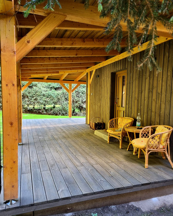 Detail terasy rekreačního domu, která je obložena terasovými prkny KI Duo, v pozadí obložení fasády fasádním obkladem KI Trend v šedé barvě. Detail terasy rekreačního domu, která je obložena terasovými prkny KI Duo, v pozadí obložení fasády fasádním obkladem KI Trend v šedé barvě.